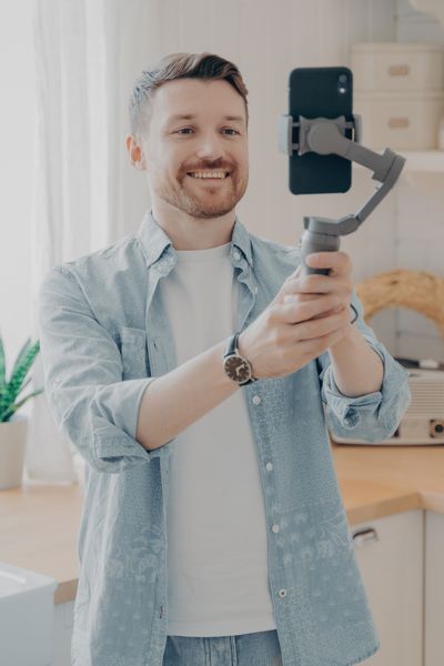 ein Mann nimmt ein Video von sich selbst mit einem Handy auf, das er auf einem beweglichen Stativ trägt