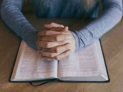 Hänge auf einer Bibel zum Gebet gefaltet