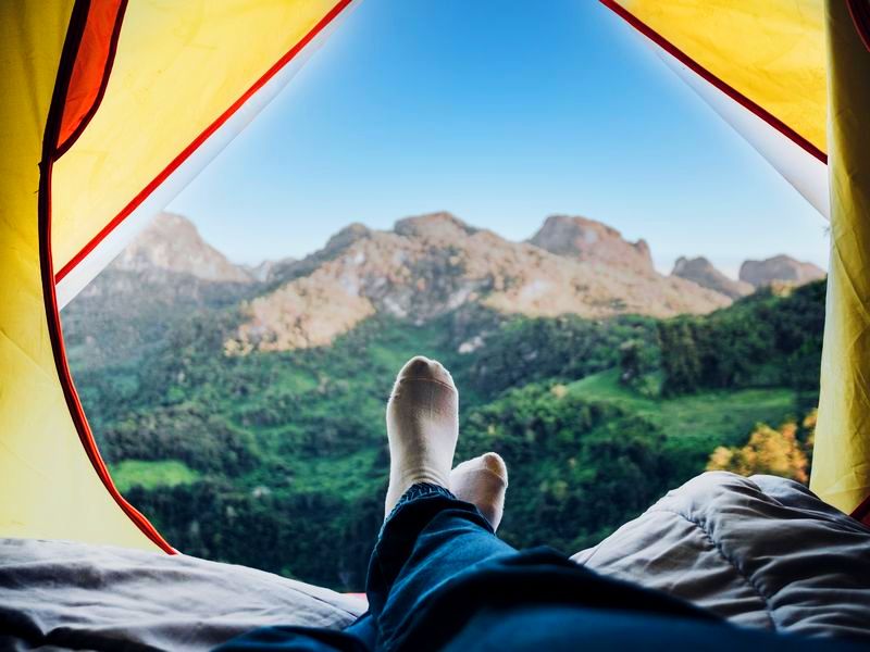 ausgestreckte Füße in einem Zelt mit Blick auf die Landschaft