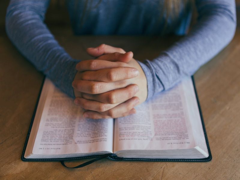 Hände sind auf einer Bibel zum Gebet gefaltet